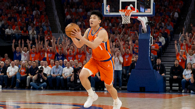 NBA篮球比赛中球员突破上篮的瞬间，体育馆内座无虚席，观众热情高涨